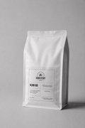 A white stand-up coffee bag with a minimalist black label reading GOOD STUFF and BLEND 001, photographed on a clean light gray background.